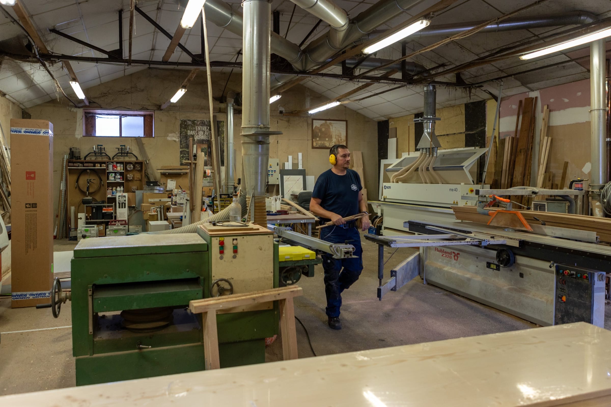 L’atelier de Bolbec, vue générale : un menuisier entre les machines